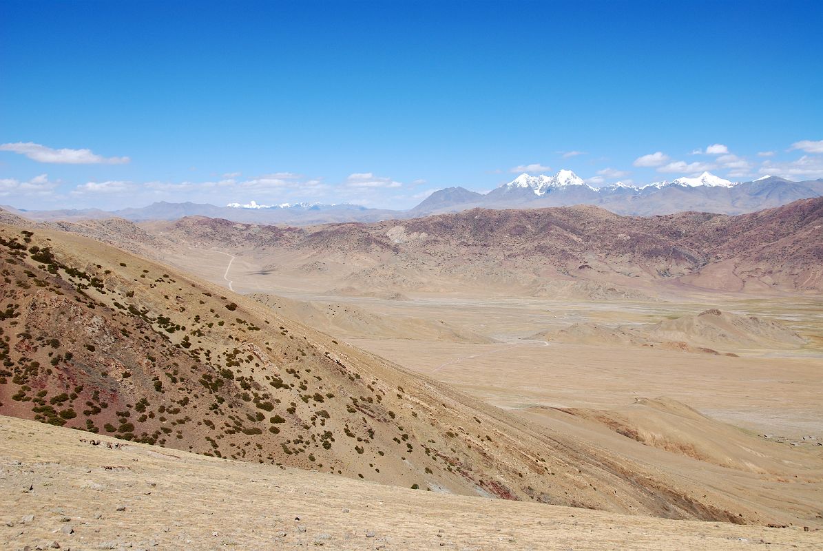 18 Pass North Of Drolung Tso Lake With View Ahead Toward Saga With 6000m Mountains Northeast Of Saga The road climbs from Drolung Tso Lake to a pass on the way to Saga with the 6000m mountains northeast of Saga visible in the distance.